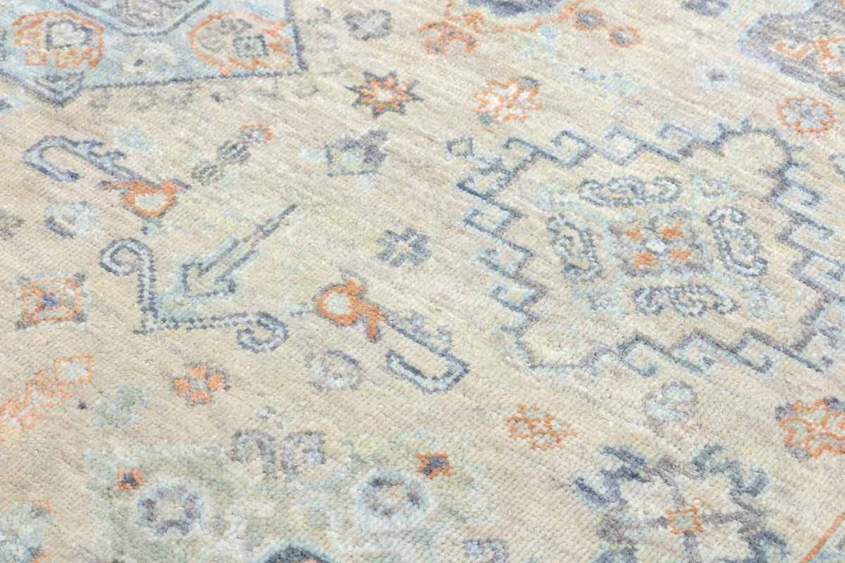 Close-up of a patterned rug with geometric designs in beige, blue, and orange.