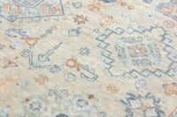 Close-up of a patterned rug with geometric designs in beige, blue, and orange.
