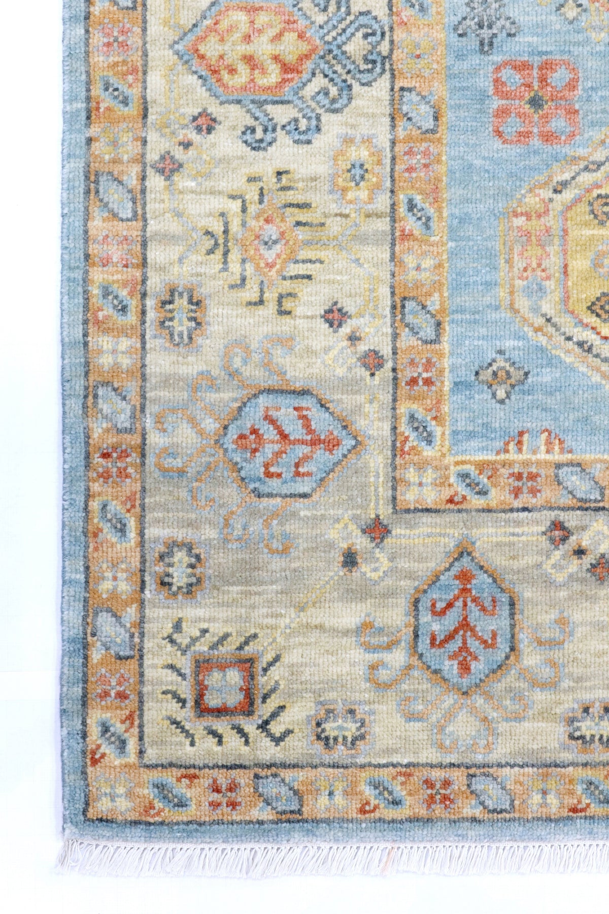 Close-up of a patterned rug with geometric designs in blue, orange, and beige.